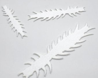 May include: Three white, spiky, feather-shaped craft foam cutouts. The cutouts vary in size and are arranged on a white background. The shapes have a textured, glittery appearance, suggesting they might be used for decorative purposes or craft projects.