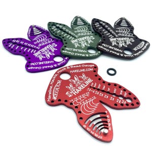 May include: A collection of Hareline Hook & Bead Gauges in various colors, including purple, green, black, and red. Each gauge features a unique shape with measurement markings and the Hareline logo. A black O-ring is also present.