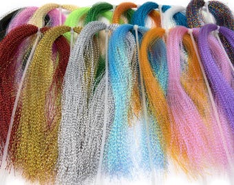 May include: A collection of colorful, shimmering strands of craft material, bundled together with white ties. The strands display a variety of colors, including red, gold, silver, blue, orange, pink, and purple. The material appears to be used for crafting or decorative purposes.
