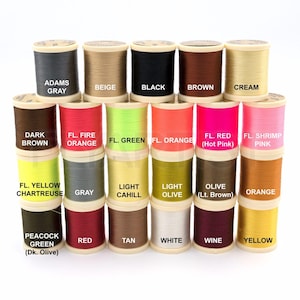 May include: A collection of colorful spools of thread, each labeled with a different color name. Colors include gray, beige, black, brown, cream, dark brown, fire orange, green, orange, hot pink, shrimp pink, yellow chartreuse, gray, light cahill, light olive, olive, orange, red, tan, white, wine, and yellow.