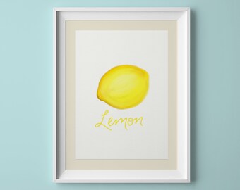 Puede incluir: Una impresión enmarcada en blanco con una ilustración de acuarela de un limón amarillo y la palabra "Lemon" en escritura amarilla.