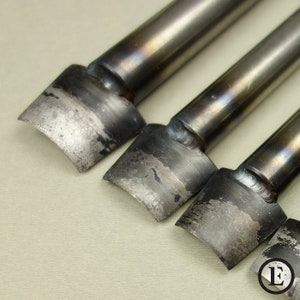 Puede incluir: Cuatro herramientas de metal para trabajar el cuero con bordes redondeados y un mango. Las herramientas se utilizan para cortar cuero.