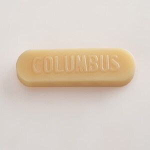 K&ouml;nnte beinhalten: Ein beigefarbener Schuhputzstift mit dem Wort "COLUMBUS" in Pr&auml;gung auf der Oberseite.