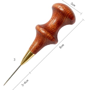 May include: A wooden leather awl with a brass tip. The awl is 8 inches long and has a 3-inch handle. The handle is made of dark wood and has a rounded shape.