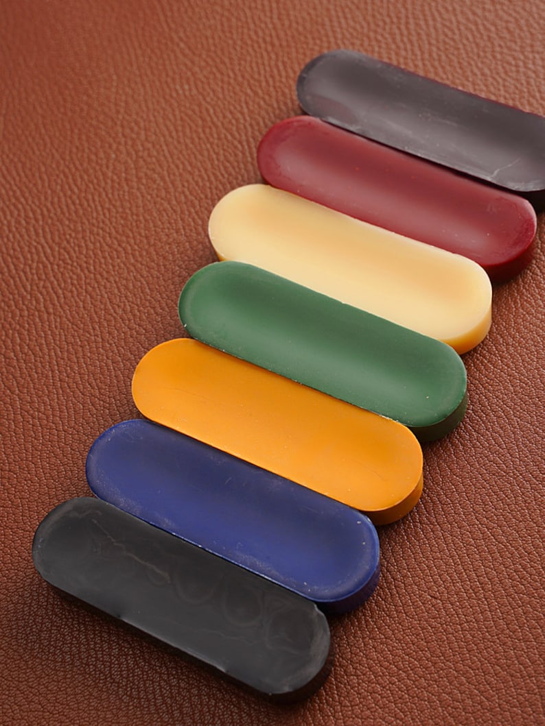 K&ouml;nnte beinhalten: Sieben unterschiedlich farbige Schuhputzst&auml;be in einer Reihe angeordnet. Die Farben sind Schwarz, Dunkelblau, Orange, Gr&uuml;n, Gelb, Rot und Dunkelgrau.