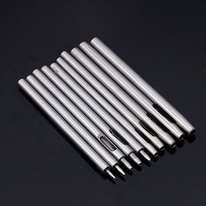 May include: Set of ten silver metal hole punch tools with different sized holes. The tools are arranged in order of size, with the smallest hole punch on the left and the largest hole punch on the right.