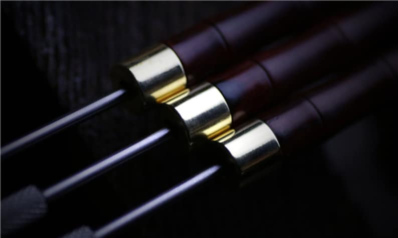 May include: Three wooden dowels with gold metal tips. The dowels are dark brown and have a smooth finish.
