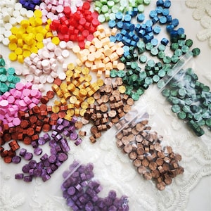 Può includere: Assortimento di timbri per sigilli di cera di vari colori, tra cui rosso, oro, verde, viola e marrone. I sigilli di cera sono in piccoli sacchetti di plastica.