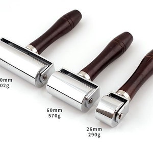 May include: Three chrome-plated leather rollers with wooden handles. The rollers are 100mm, 60mm, and 26mm in diameter. The weights are 902g, 570g, and 290g.