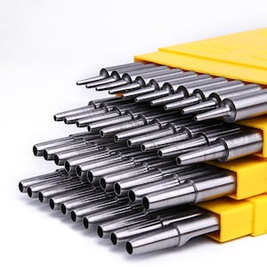 Può includere: Un set di strumenti di punzonatura in metallo in una custodia di plastica gialla. Gli strumenti sono disposti in ordine di dimensione, con il più piccolo in alto e il più grande in basso.