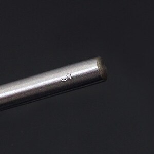 May include: Close-up of a silver metal rod with the number "1" engraved on the side.