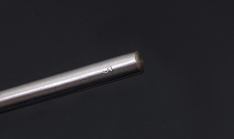 May include: Close-up of a silver metal rod with the number "1" engraved on the side.