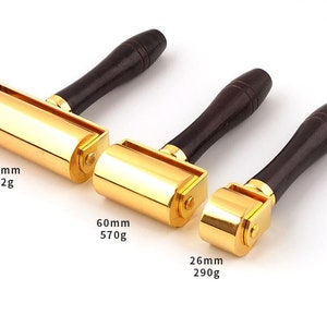 May include: Three gold-colored leather rolling tools with wooden handles. The tools are 100mm, 60mm, and 26mm in size and weigh 902g, 570g, and 290g respectively.