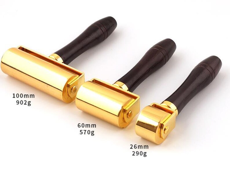 May include: Three gold-colored leather rolling tools with wooden handles. The tools are 100mm, 60mm, and 26mm in size and weigh 902g, 570g, and 290g respectively.