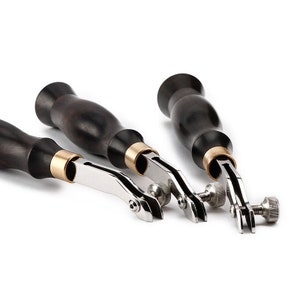 May include: Three leather working tools with wooden handles and metal working parts. The tools are used for stitching leather.
