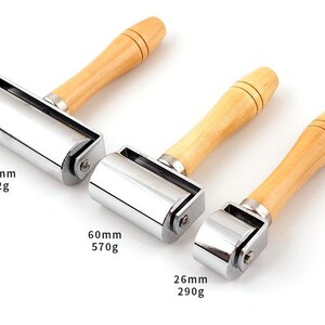 May include: Three metal rolling tools with wooden handles. The rollers are 100mm, 60mm, and 26mm in diameter. The weights are 902g, 570g, and 290g.