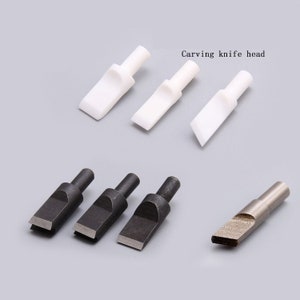 Puede incluir: Conjunto de seis cabezales de cuchillo para tallar, tres de cerámica blanca y tres de metal negro. El texto "Carving knife head" es visible en la imagen.