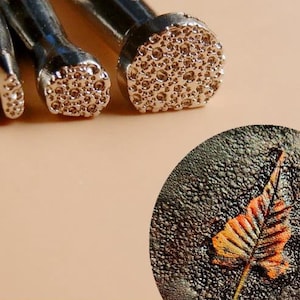 Pode incluir: Três ferramentas de estampagem de metal com pontas redondas texturizadas. As ferramentas são usadas para o artesanato em couro e criam um padrão texturizado no couro.