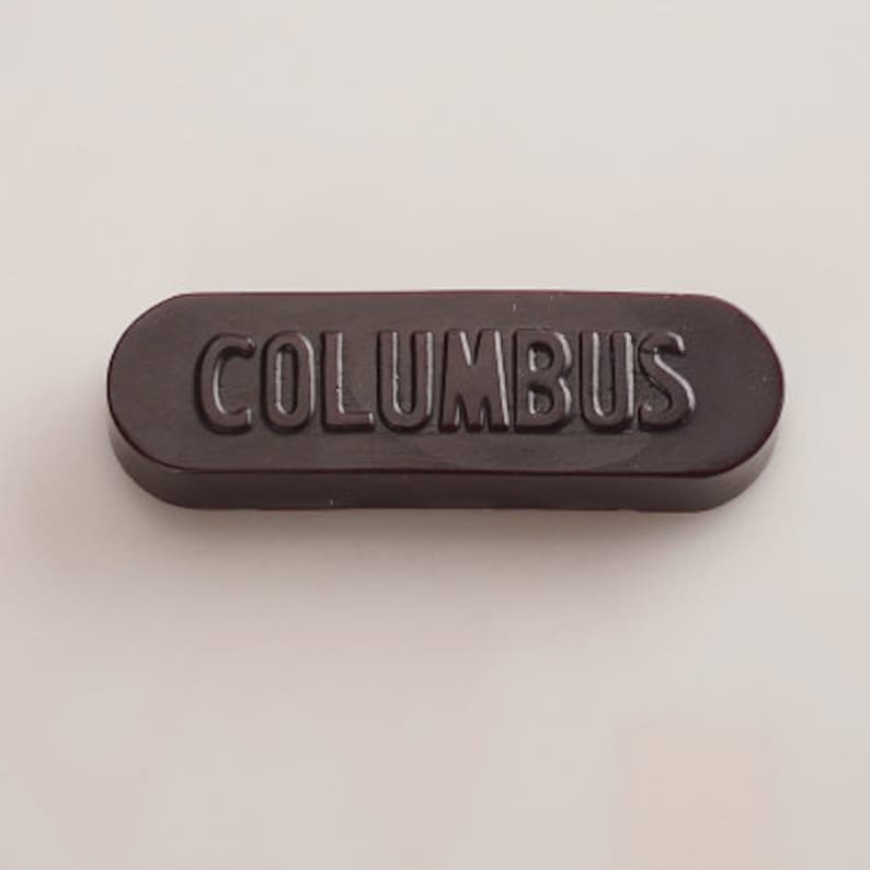 K&ouml;nnte beinhalten: Ein dunkelbraunes, ovalf&ouml;rmiges Siegelwachs mit dem Wort "COLUMBUS" in wei&szlig;en Lettern gepr&auml;gt.