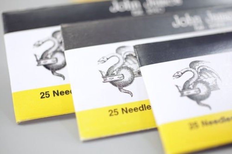 May include: Three packages of sewing needles with a yellow label and a black and white illustration of a dragon. The label reads "25 Needles".