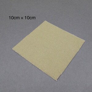 May include: A 10cm by 10cm square piece of beige canvas fabric.