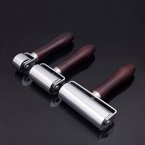 May include: Three leather working tools with wooden handles and metal rollers. The rollers are different sizes.