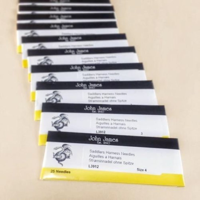 May include: A pack of 25 size 4 saddlers harness needles from John James, est. 1840. The needles are packaged in a yellow and black wrapper with a dragon illustration. The text on the wrapper reads "Saddlers Harness Needles, Aiguilles a Harnais, Straminnadel ohne Spitze, L3912, 25 Needles, Size 4".