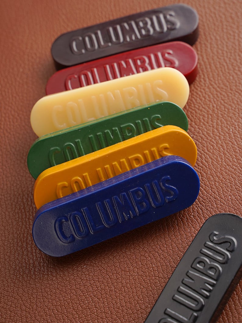 K&ouml;nnte beinhalten: Sechs Schuhputzstift in verschiedenen Farben, darunter Schwarz, Rot, Gelb, Gr&uuml;n und Blau. Jeder Stift ist mit "COLUMBUS" beschriftet.