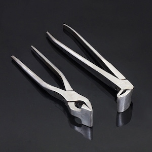 Puede incluir: Dos alicates de metal plateado con mordazas planas. Los alicates están sobre una superficie negra.