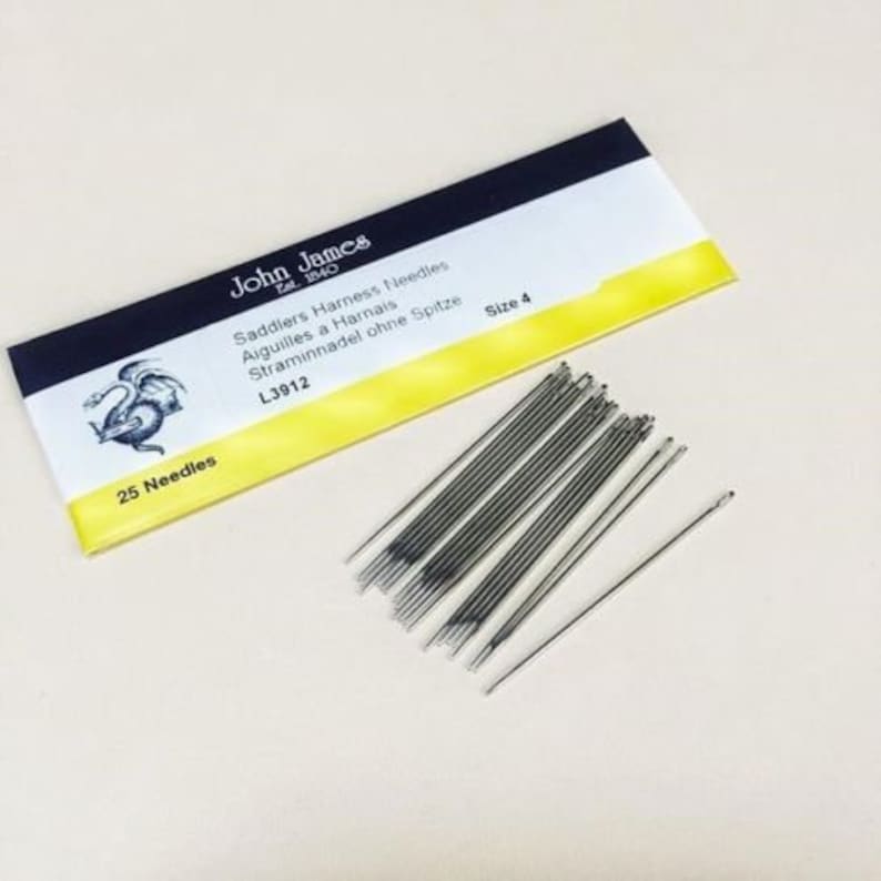 May include: A package of 25 silver saddlers harness needles, size 4, from John James, est. 1840. The package is yellow and black with a dragon illustration and the text "Saddlers Harness Needles, Aiguilles a Harnais, Straminnadel ohne Spitze, L3912, Size 4".