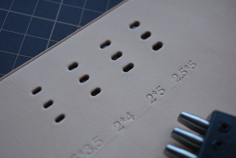 Pu&ograve; includere: Primo piano di una superficie in pelle marrone chiaro con pi&ugrave; fori rotondi punzonati in un motivo. La superficie &egrave; contrassegnata dai numeri "2*3.5", "2*4" e "2*5.5".