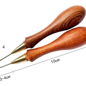 May include: Two wooden awls with brass tips. The awls are 10 cm long and have a 2 cm diameter. The awls are used for leather crafting.