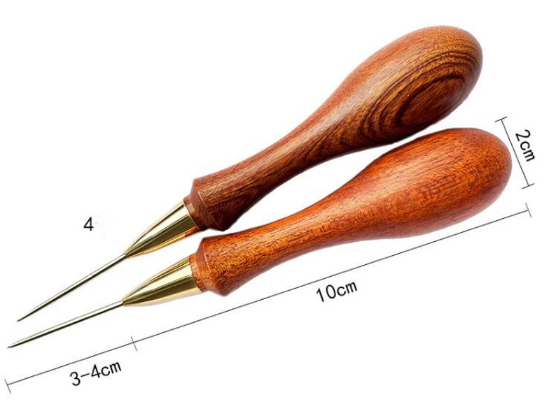 May include: Two wooden awls with brass tips. The awls are 10 cm long and have a 2 cm diameter. The awls are used for leather crafting.