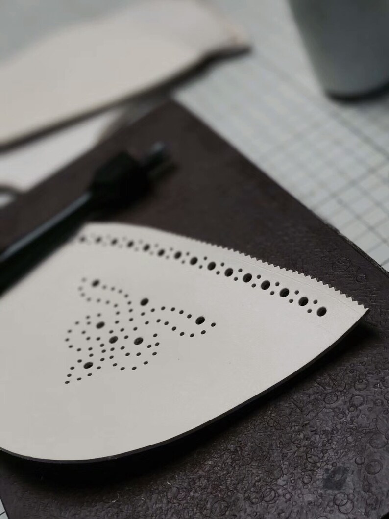 May include: A white ironing board cover with a decorative pattern of small holes. The cover is on a dark brown surface.