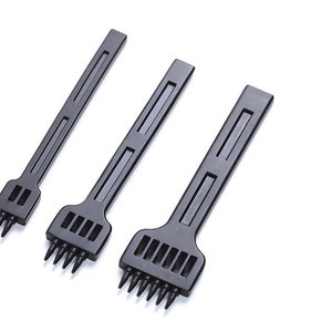 Può includere: Tre strumenti di punzonatura in pelle neri con fori di diverse dimensioni. Gli strumenti sono in plastica e hanno un manico.