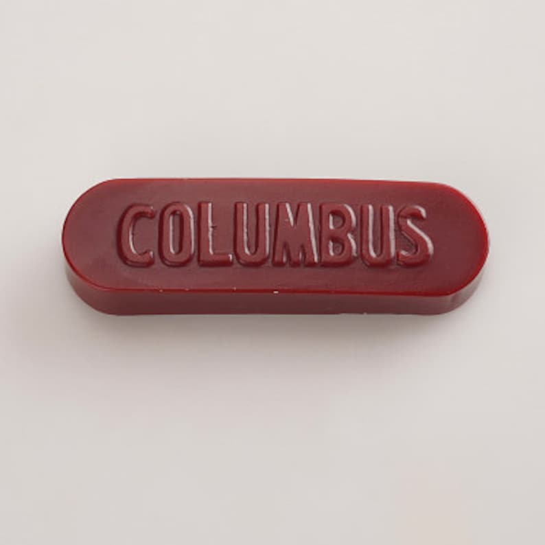 K&ouml;nnte beinhalten: Ein rotes Siegelwachs mit dem Wort "COLUMBUS" in wei&szlig; gepr&auml;gt.
