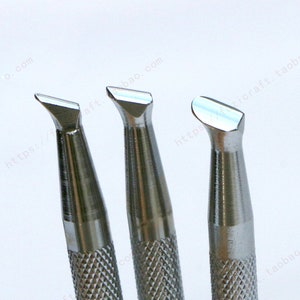 Può includere: Tre strumenti in metallo con punte di forme diverse, tutti con un'impugnatura testurizzata. Gli strumenti sono utilizzati per la lavorazione del cuoio.