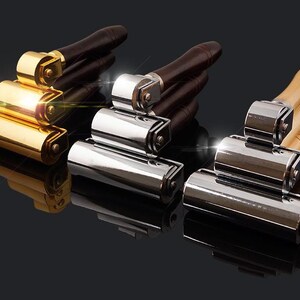 May include: Three rolling tools with wooden handles. The tools have different finishes: gold, silver, and chrome. The tools are stacked on top of each other.