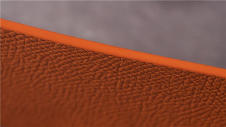 May include: Close-up of a textured orange leather surface. The leather has a fine grain pattern.