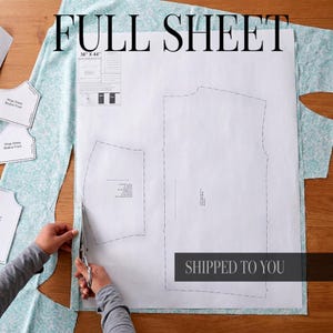 May include: A white paper sewing pattern labeled "FULL SHEET" with dimensions 36" x 44". The pattern is placed on a light blue patterned fabric. The text "SHIPPED TO YOU" is visible. Scissors are cutting the fabric.
