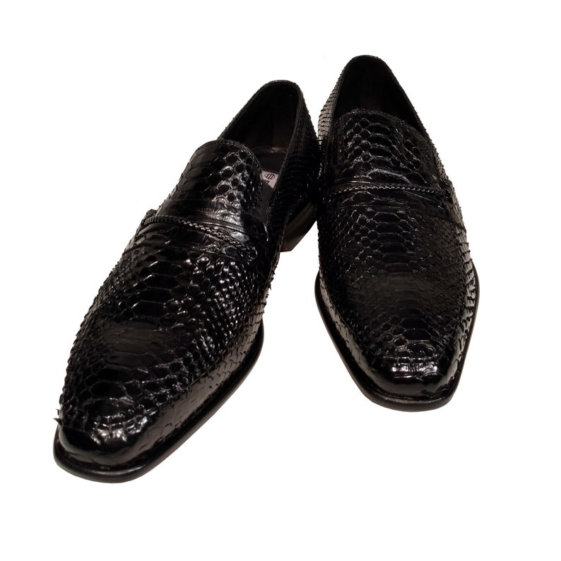 May include: A pair of black leather slip-on shoes with a snakeskin pattern.