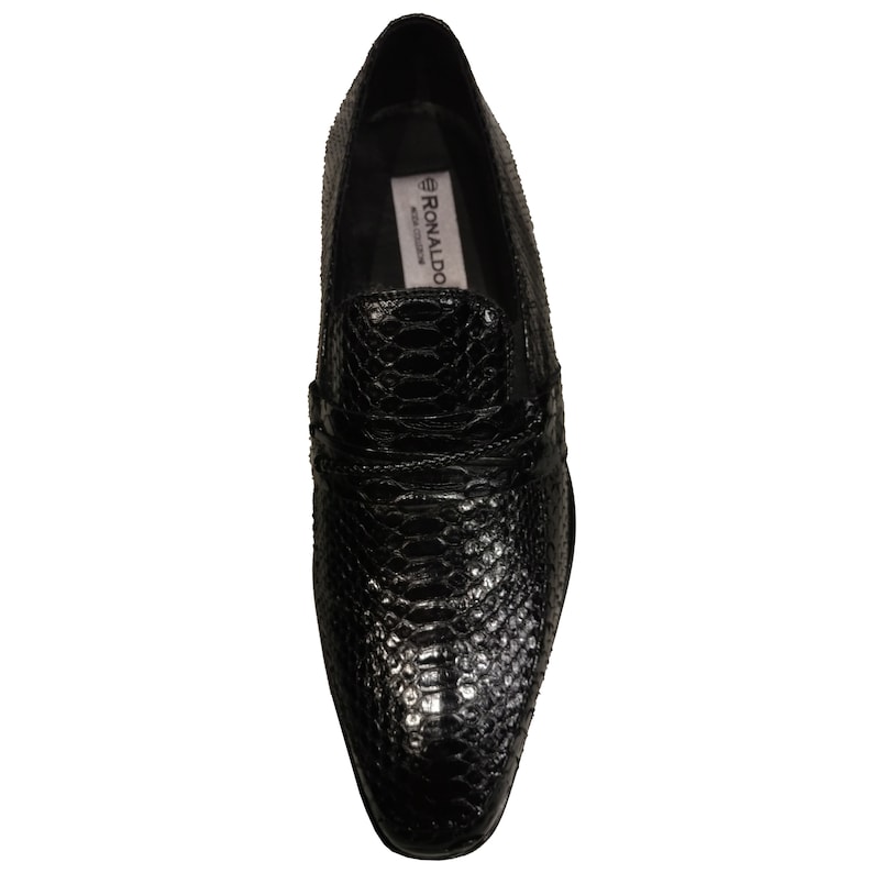 May include: Black leather slip-on shoes with a snakeskin pattern. The shoes have a pointed toe and a low heel. The brand name "RONALDO" is visible on the inside of the shoe.