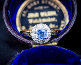Anel vintage em ouro 18 quilates com halo de safiras azuis e diamantes redondos em formato de cluster.