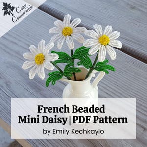 Op de afbeelding: Een kleine witte kruik bevat een boeket van kralenmadeliefjes. De madeliefjes hebben witte bloemblaadjes en gele centra. Groene kralenbladeren en stelen ondersteunen de bloemen. De tekst "French Beaded Mini Daisy | PDF Pattern" wordt weergegeven.