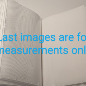 Puede incluir: Un &aacute;lbum de fotos blanco con una cubierta texturizada y una p&aacute;gina blanca abierta para mostrar el interior. El texto "Last images are for measurements only" est&aacute; impreso en la p&aacute;gina abierta.