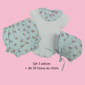 Puede incluir: Un conjunto de ropa de bebé de tres piezas en estampado floral azul claro. El conjunto incluye un body con cuello fruncido, bombachos y un gorro.  Set 3 pièces + de 30 tissus au choix