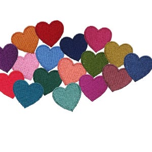 Peut inclure: Un ensemble de patchs en forme de cœur brodés de différentes couleurs, dont le rouge, le rose, le bleu, le vert et le violet. Les patchs sont disposés en grappe sur fond blanc.