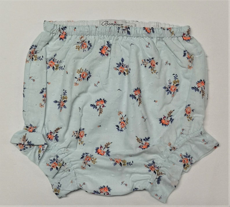 Puede incluir: Bombacho de beb&eacute; azul claro con estampado floral y cintura el&aacute;stica blanca. El bombacho tiene un borde con volantes y dice "Bonjour" en la cintura.