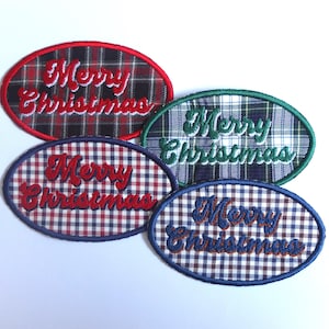 Puede incluir: Cuatro parches navideños ovalados con patrones de cuadros en rojo, verde, azul y marino. Cada parche tiene las palabras "Merry Christmas" bordadas en un color contrastante, creando un tema festivo navideño.