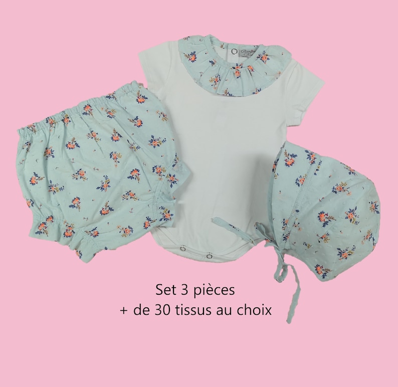 Puede incluir: Un conjunto de ropa de beb&eacute; de tres piezas en estampado floral azul claro. El conjunto incluye un body con cuello fruncido, bombachos y un gorro.  Set 3 pi&egrave;ces + de 30 tissus au choix